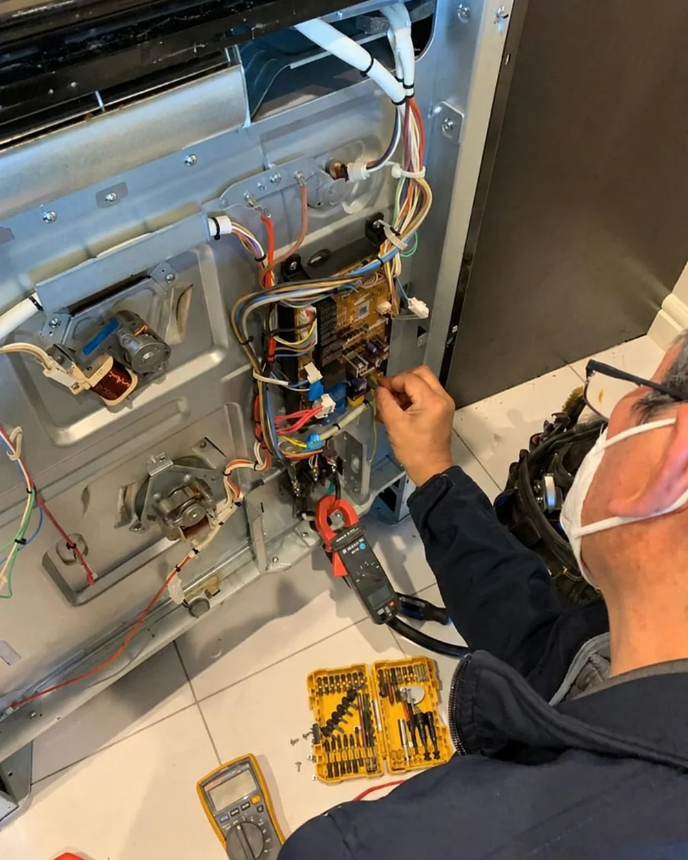 Technician testing an appliance electrical panel with diagnostic equipment