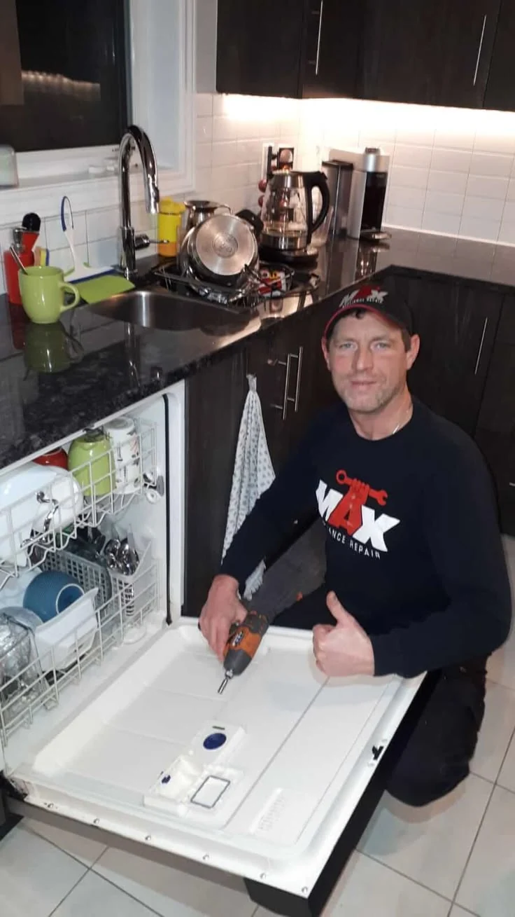 Appliance technician working beside an open dishwasher